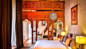 Une chambre d’hôtel avec un grand lit, une cloison en bois, un lustre et un tableau encadré au mur.