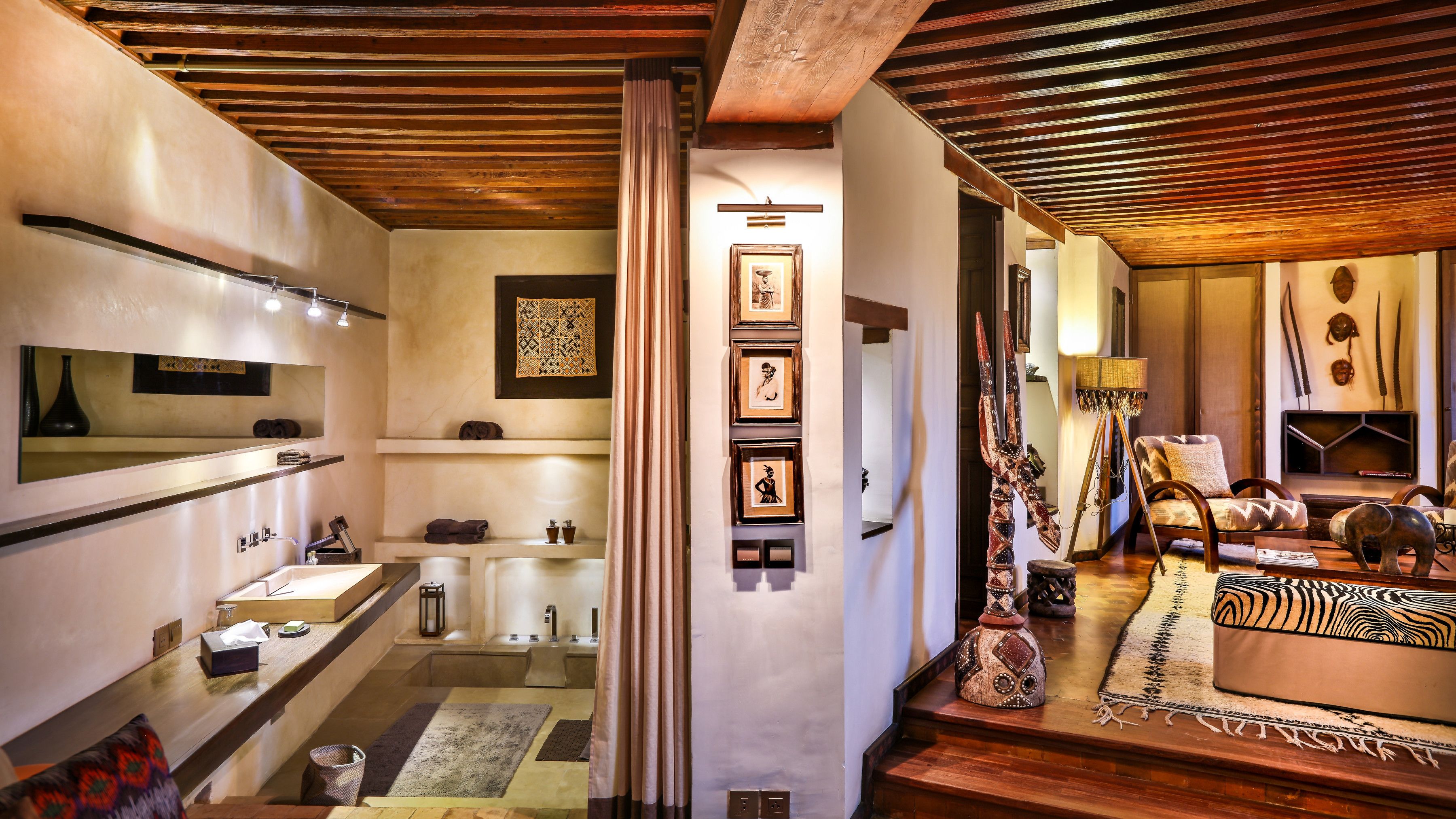 A modern interior with a wooden ceiling, a bathroom with a large mirror, and a seating area with a patterned rug.