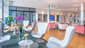 A modern hotel lobby with comfortable seating, a reception area, and a large window offering views. - Aquatis Hotel (Lausanne)