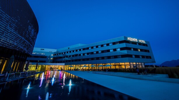 A modern hotel with a flat roof, multiple floors, and a well-lit entrance. - Aquatis Hotel (Lausanne)