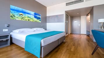 Una habitación de hotel moderna con una cama grande, un escritorio y una silla. Hay un mapa en la pared y una ventana grande con vista a una tortuga.