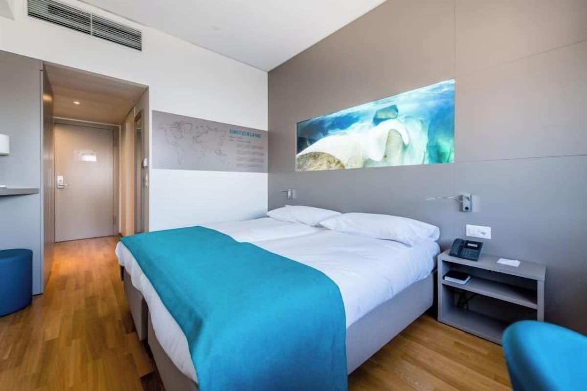 Een moderne hotelkamer met een bed, een bureau en een televisie aan de muur.