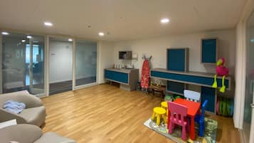 Una habitación con piso de madera, un sofá, una mesa con sillas, un microondas y un televisor.
