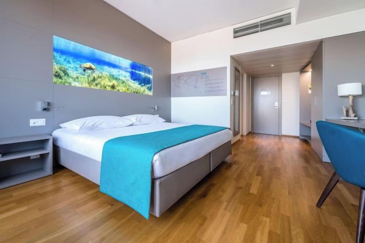 Een moderne hotelkamer met een bed, een bureau en een stoel.
