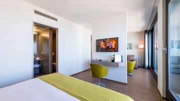 A modern hotel room with a bed, a desk, a chair, and a television.