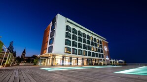 A modern hotel with a large pool area, multiple floors, and a prominent hotel sign. - Lake Geneva Hotel (Versoix)