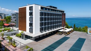 A modern hotel with a rooftop pool, a view of the sea, and a restaurant area. - Lake Geneva Hotel (Versoix)