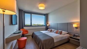 A modern hotel room with two beds, a desk, and a chair.