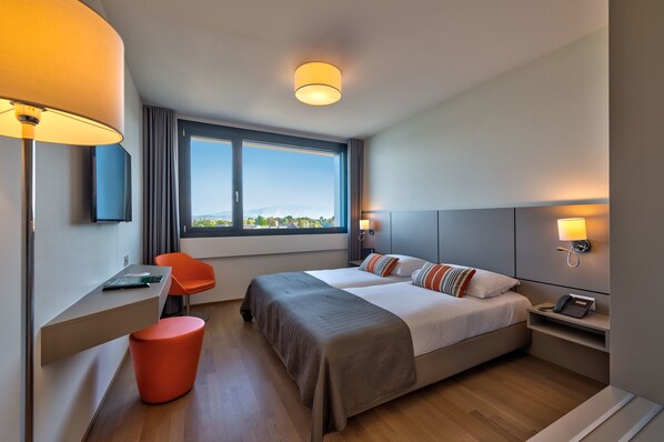 Una habitación de hotel moderna con dos camas, un escritorio y una silla.
