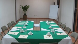 Ein Konferenzraum mit einem langen Tisch, vorbereitet für eine Besprechung, ausgestattet mit Stühlen, einer Whiteboard-Tafel und einem Blumentopf.