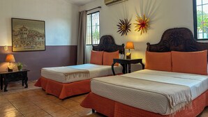 A hotel room with two beds, a nightstand, a lamp, a wall-mounted air conditioner, and a window with curtains. - Hotel La Posada del Angel (San Salvador)