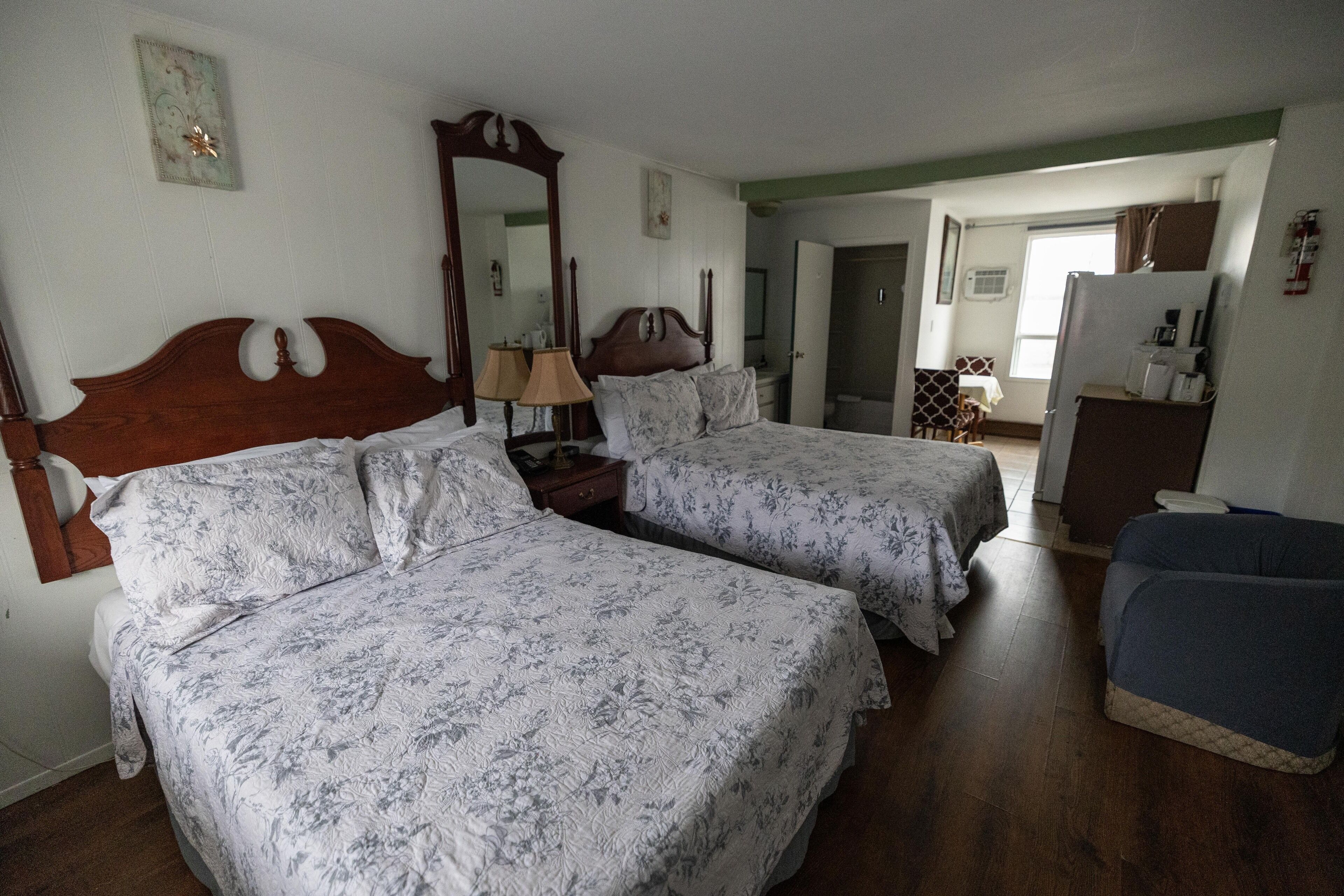 Een kamer met twee bedden, een spiegel, een dressoir en een stoel.