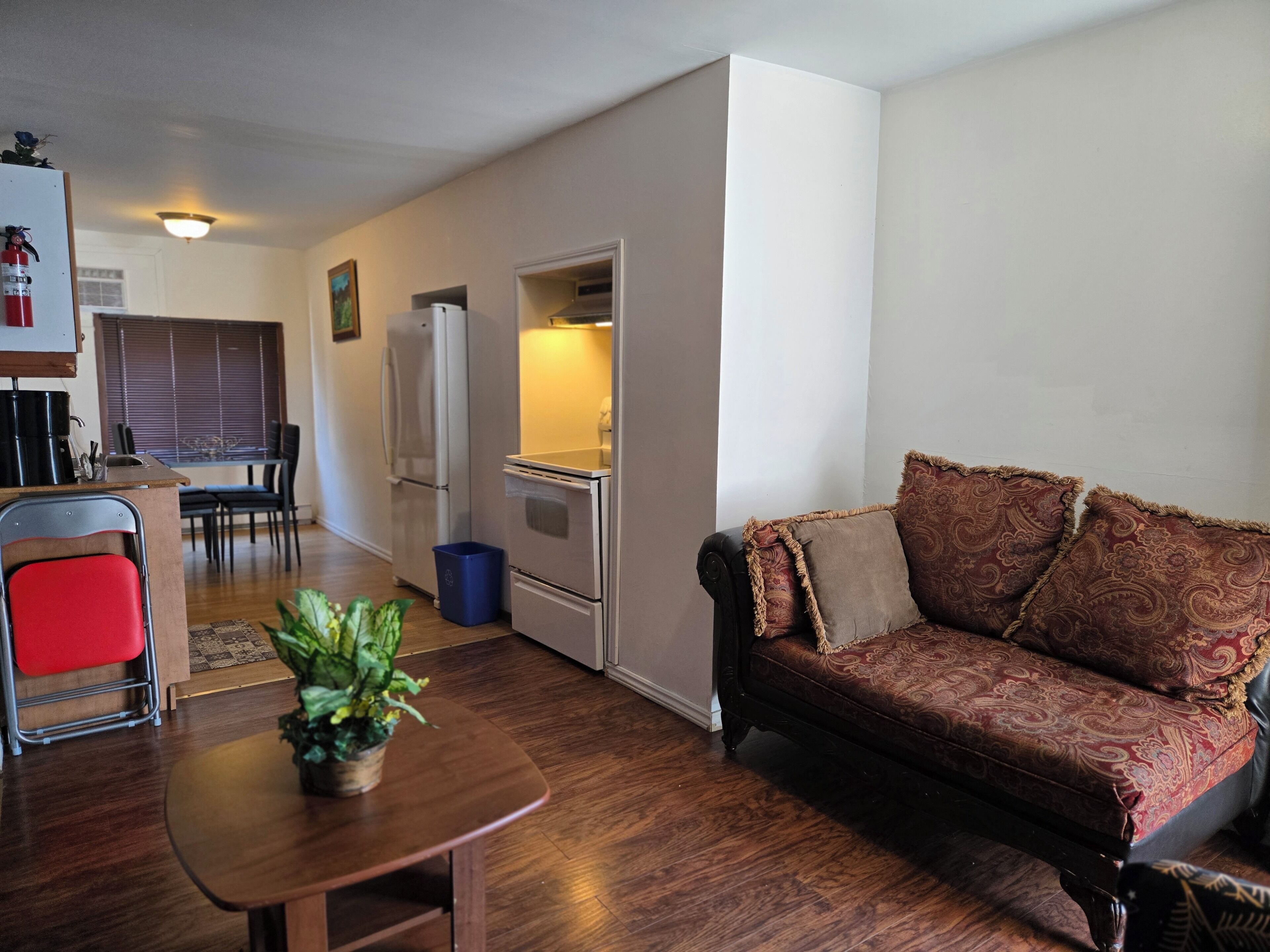 Een compacte woonruimte met een kitchenette, een eethoek en een bank.