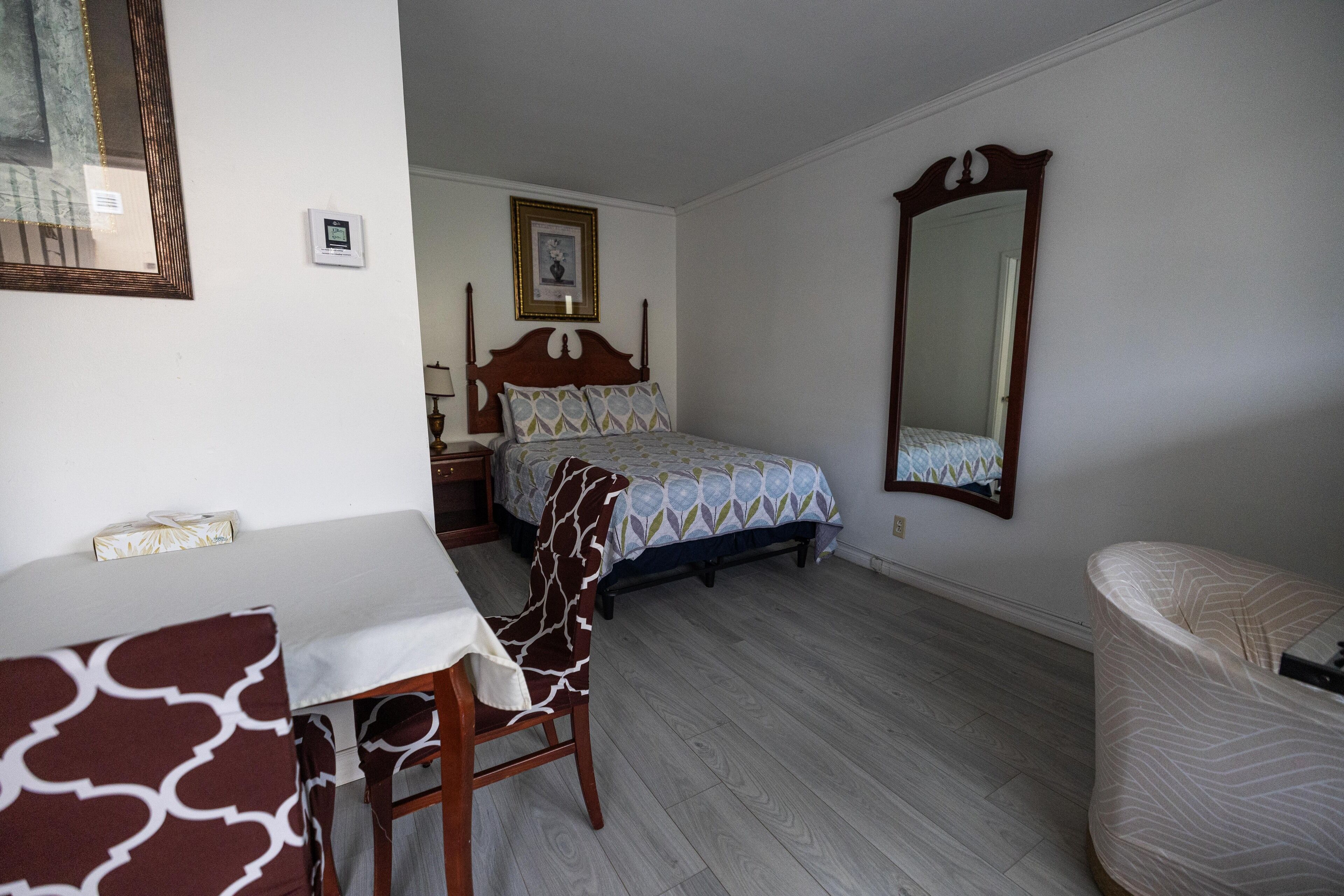 Un dormitorio con cama, una silla, una mesa y un espejo.