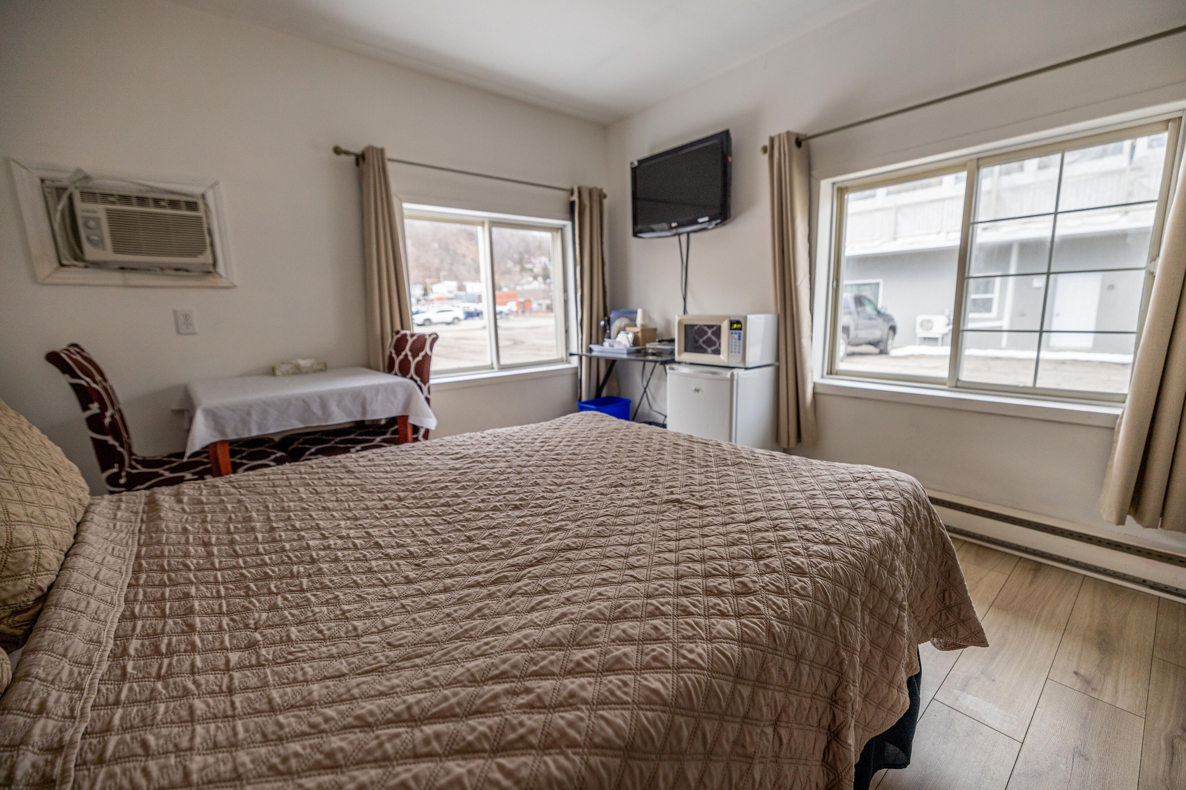 Habitación de hotel con una cama grande, un escritorio con computadora, un televisor y ventana con vista al exterior.