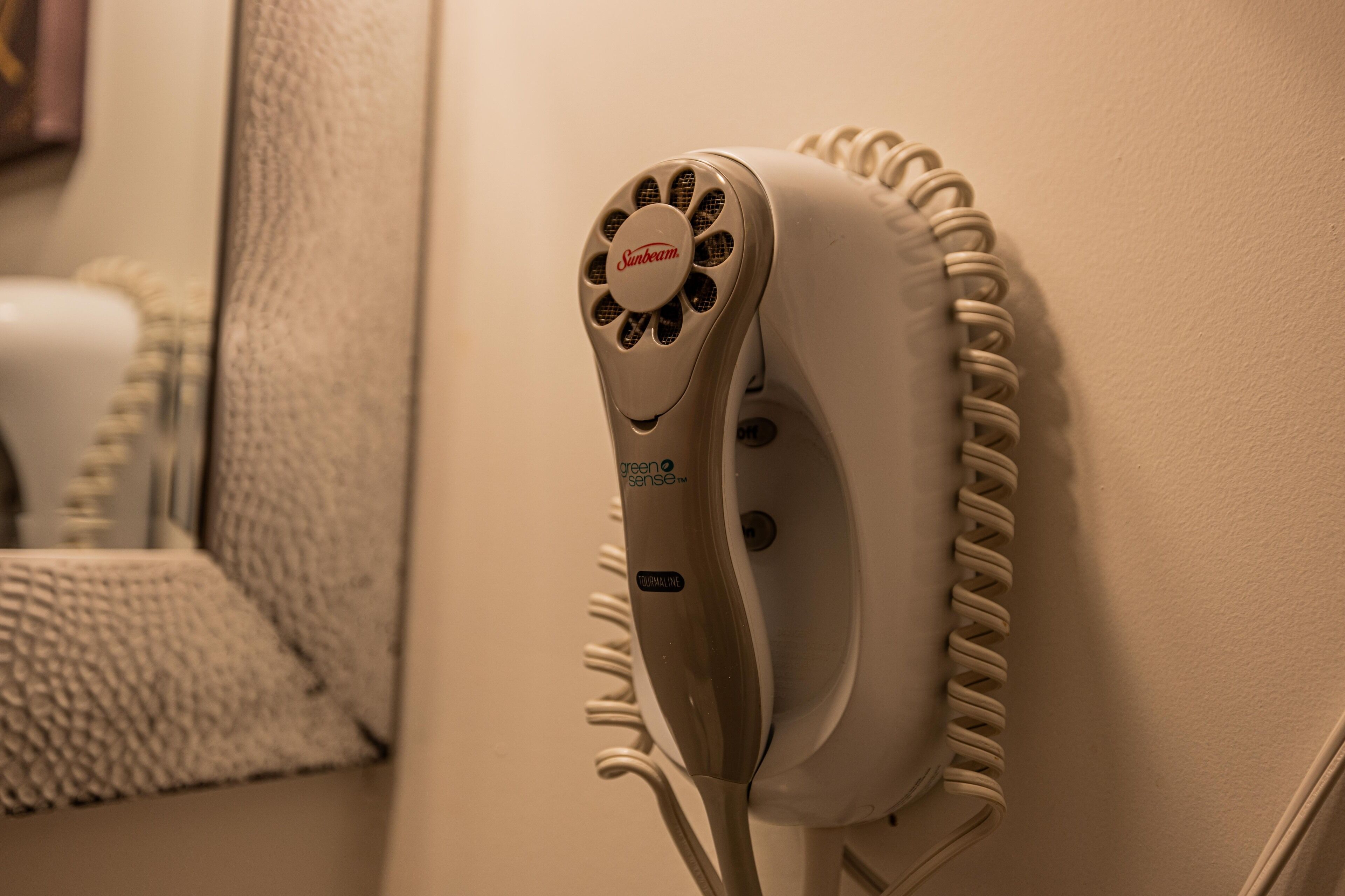 A hair dryer mounted on a wall with a towel rack nearby.