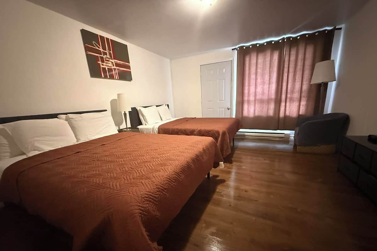 Hotellihuone, jossa on kaksi sänkyä, työpöytä, tuoli, lamppu ja ovi.