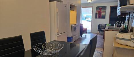 Une cuisine compacte comprenant une table à manger, des chaises, un réfrigérateur et un four à micro-ondes.