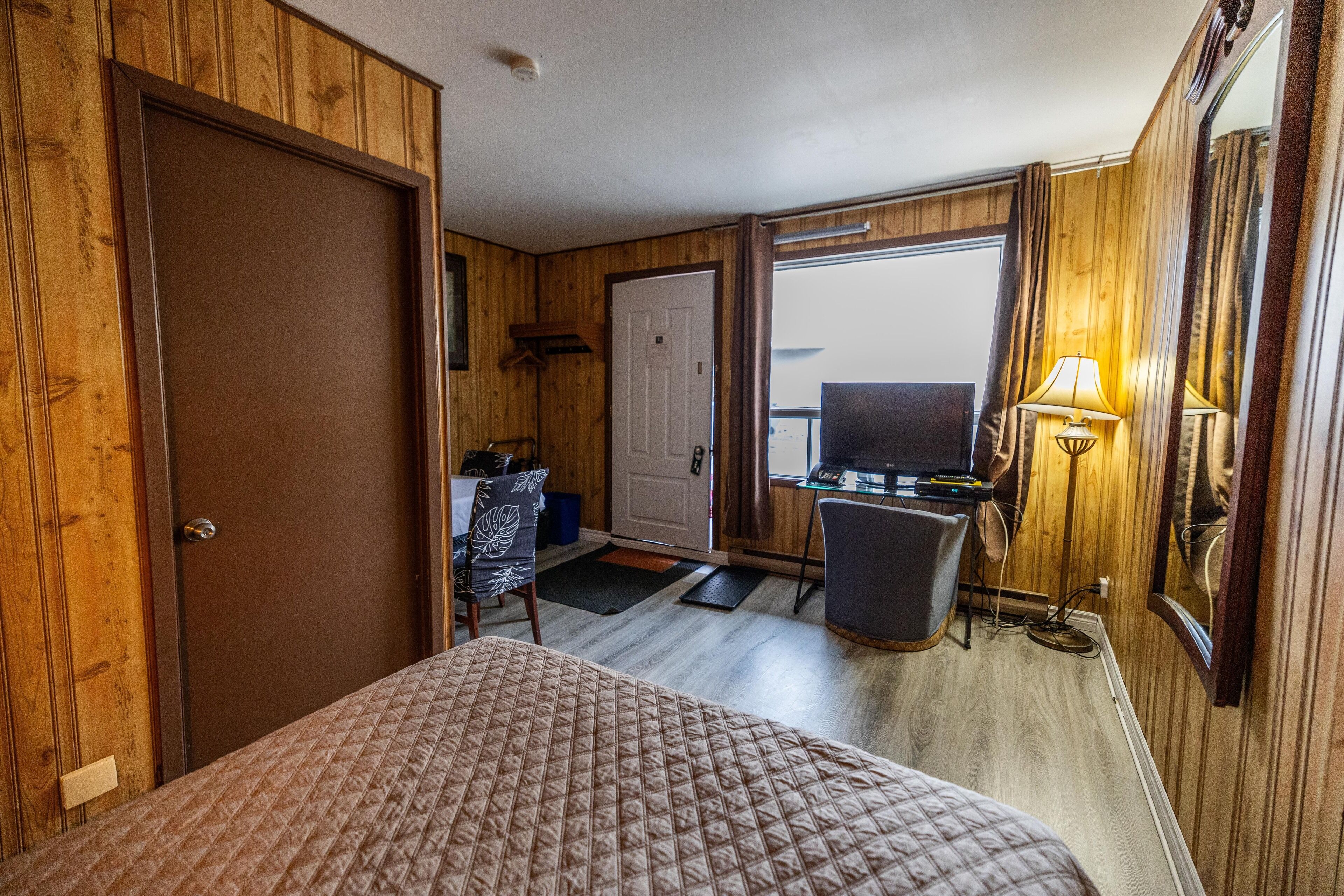 A room with a bed, a desk, a chair, and a television.
