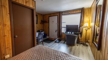 A room with a bed, a desk, a chair, and a television.