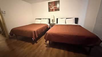 Ein Hotelzimmer mit zwei Einzelbetten, einem Nachttisch mit Lampe und einem an der Wand befestigten, abstrakten Kunstwerk.