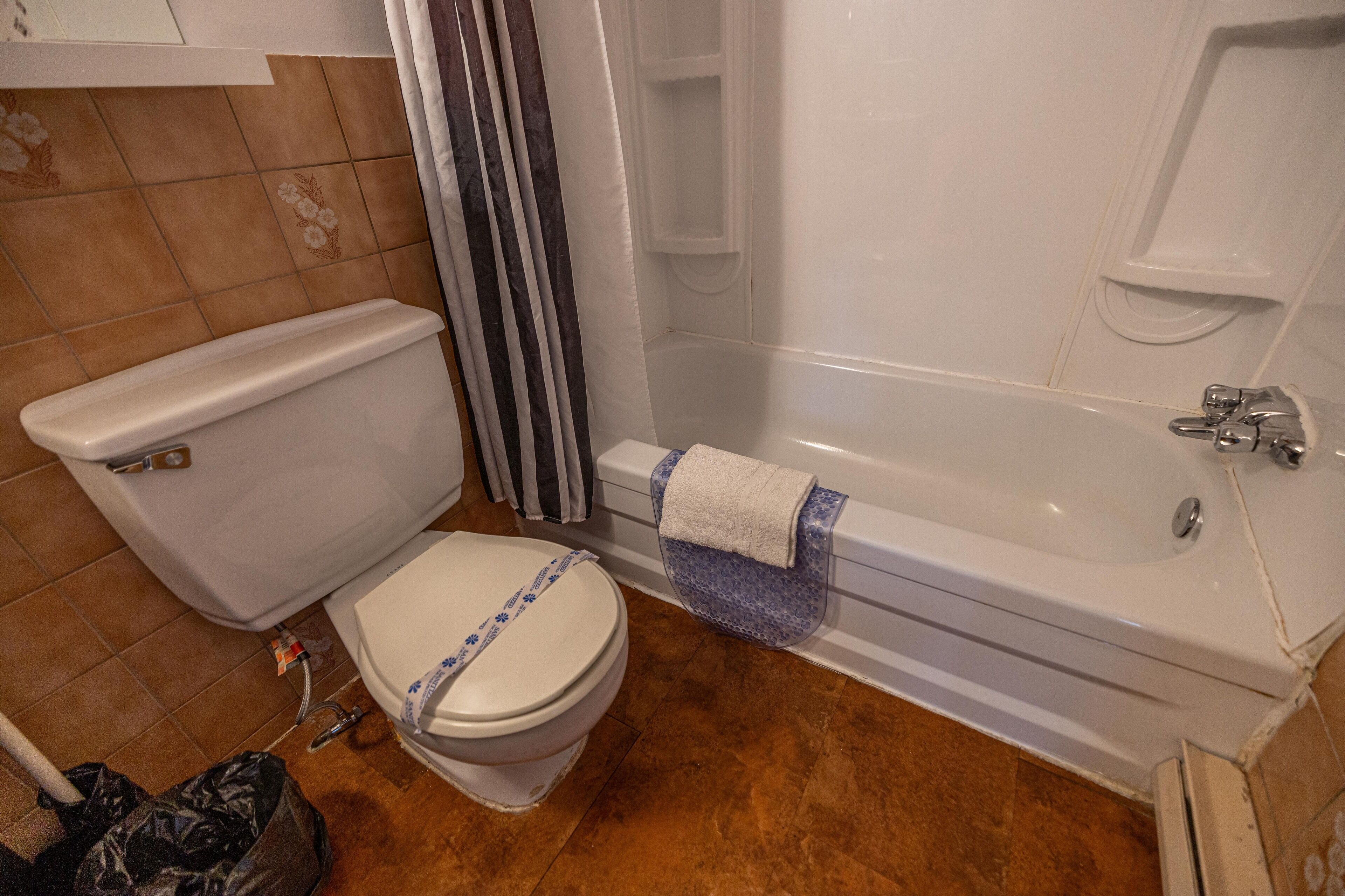 A bathroom with a toilet, bathtub, and shower area.