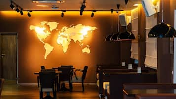 A restaurant interior with a world map on the wall, tables, chairs, and pendant lighting.