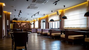 Un ristorante spazioso con pavimento in legno, diverse zone salotto e illuminazione a sospensione.