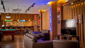 Un'area bar con tavolo da biliardo, sgabelli da bar e schermo televisivo.