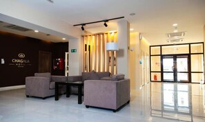 A modern lobby with sofas, a table, and a reception desk. - Chagala Hotel Bautino (Fort Shevchenko)