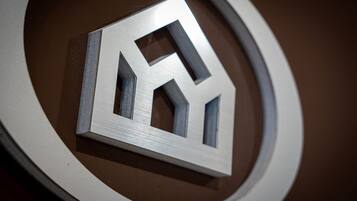 Un logo métallique aux formes géométriques, sur un fond circulaire.
