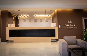 Una recepción con diseño moderno, un reloj y un letrero del Hotel Chagala.