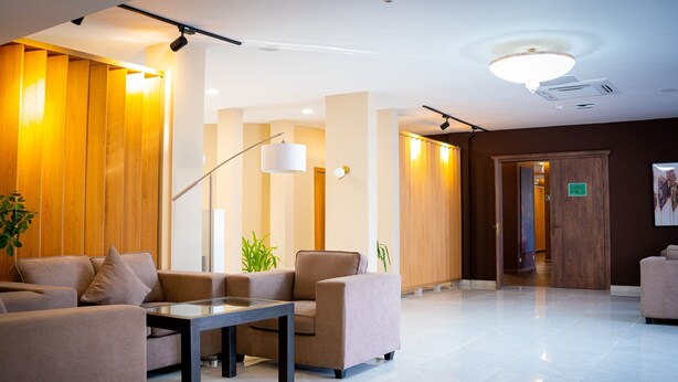Una hall moderna con reception, area lounge e un pannello in legno.