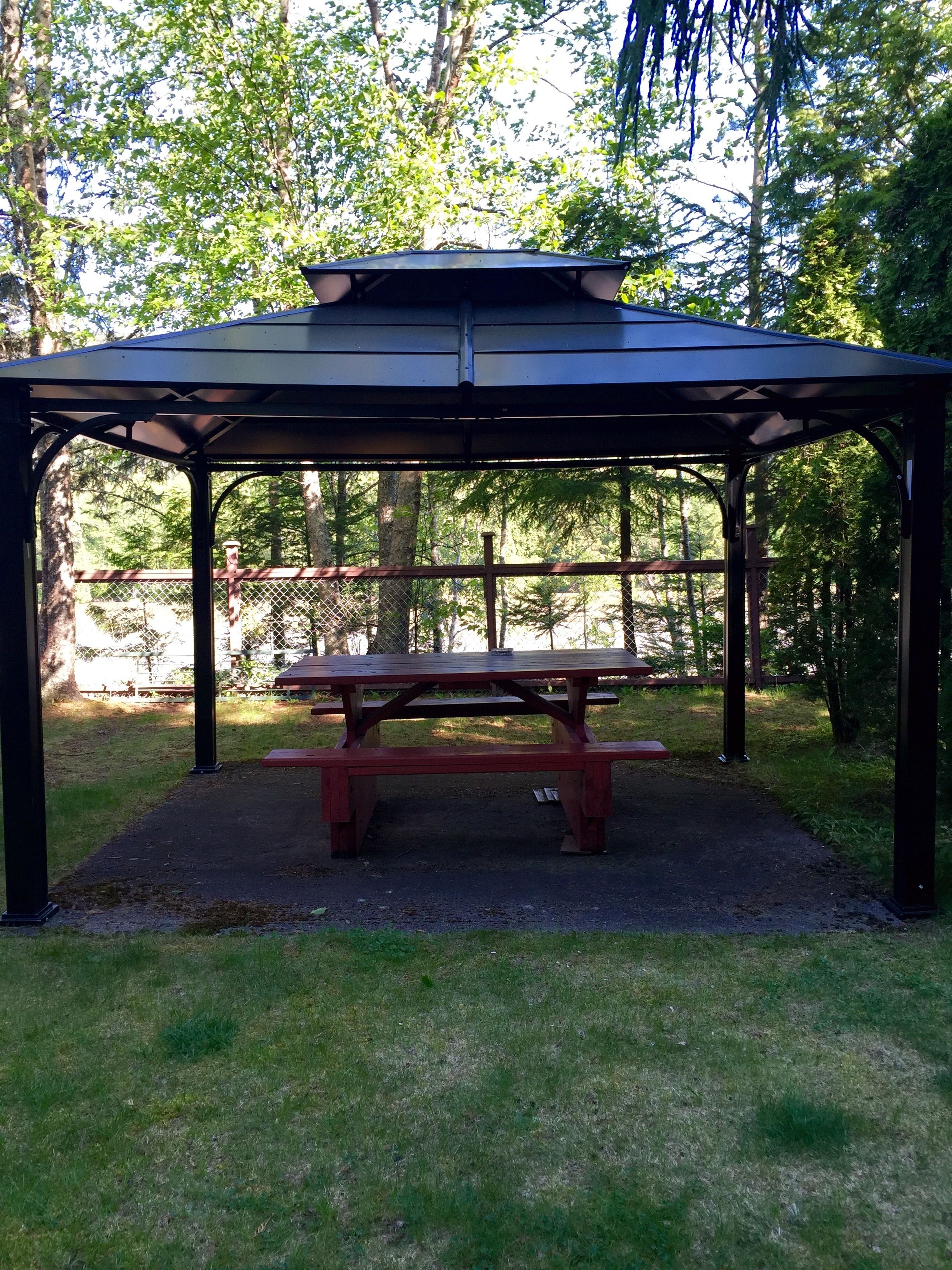 A gazebo with a picnic table in a park.