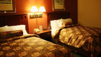 Une chambre d’hôtel avec deux lits, chacun agrémenté de draps à motifs, une table de chevet avec un téléphone et des lampes fixées au mur.