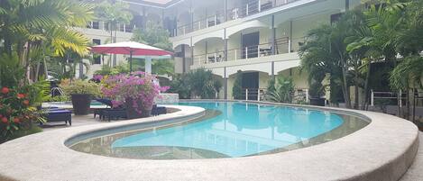 Een buitenzwembad, parasols bij het zwembad en ligstoelen