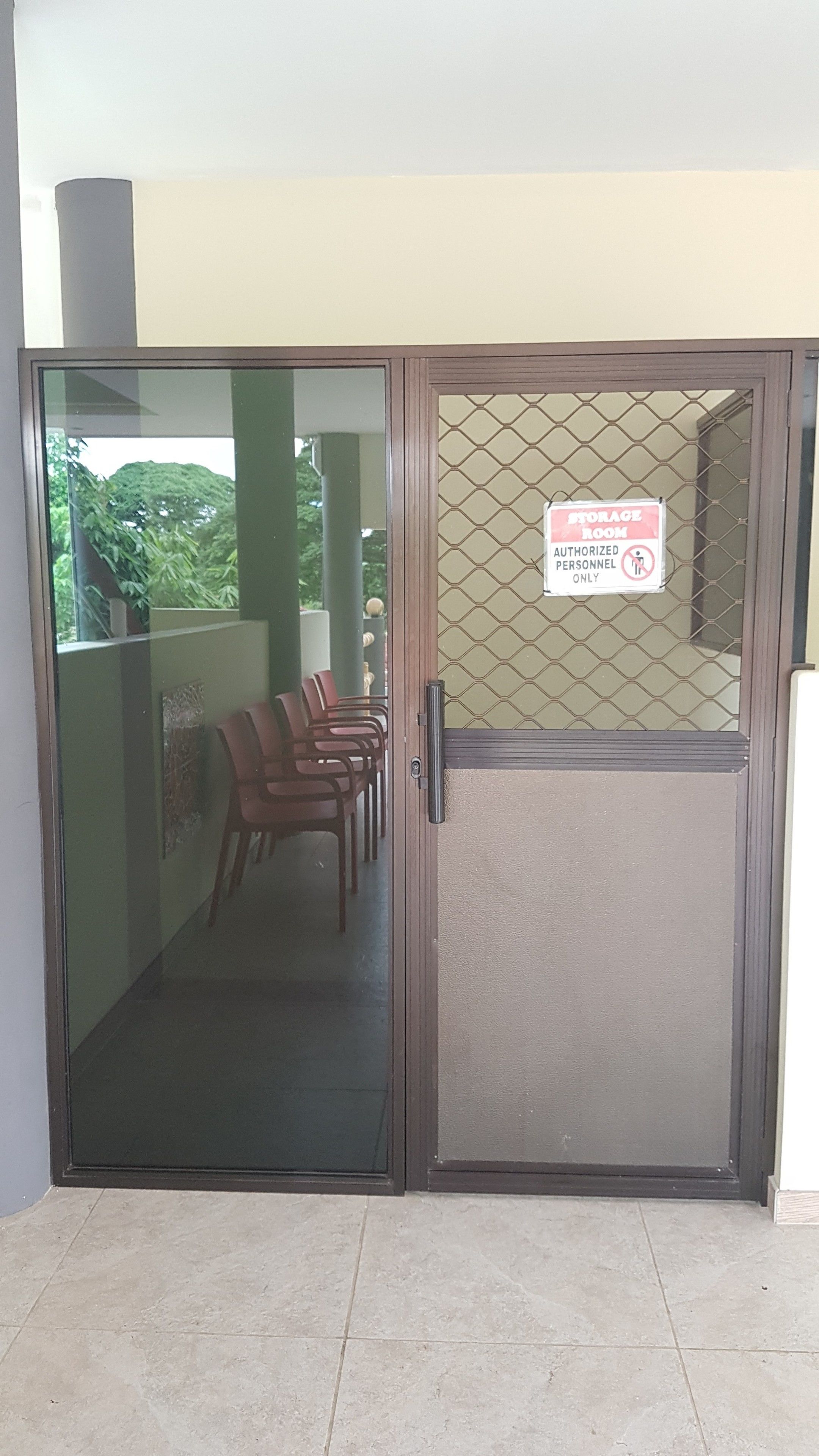 A door with a sign indicating a storage room, a glass door, and a view of chairs outside.