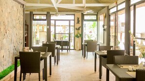 En restaurang med möbler av rotting, stenmurar och stora fönster.