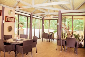 A spacious indoor area with a high ceiling, large windows, and wicker furniture. - Alona Northland Resort (Panglao)