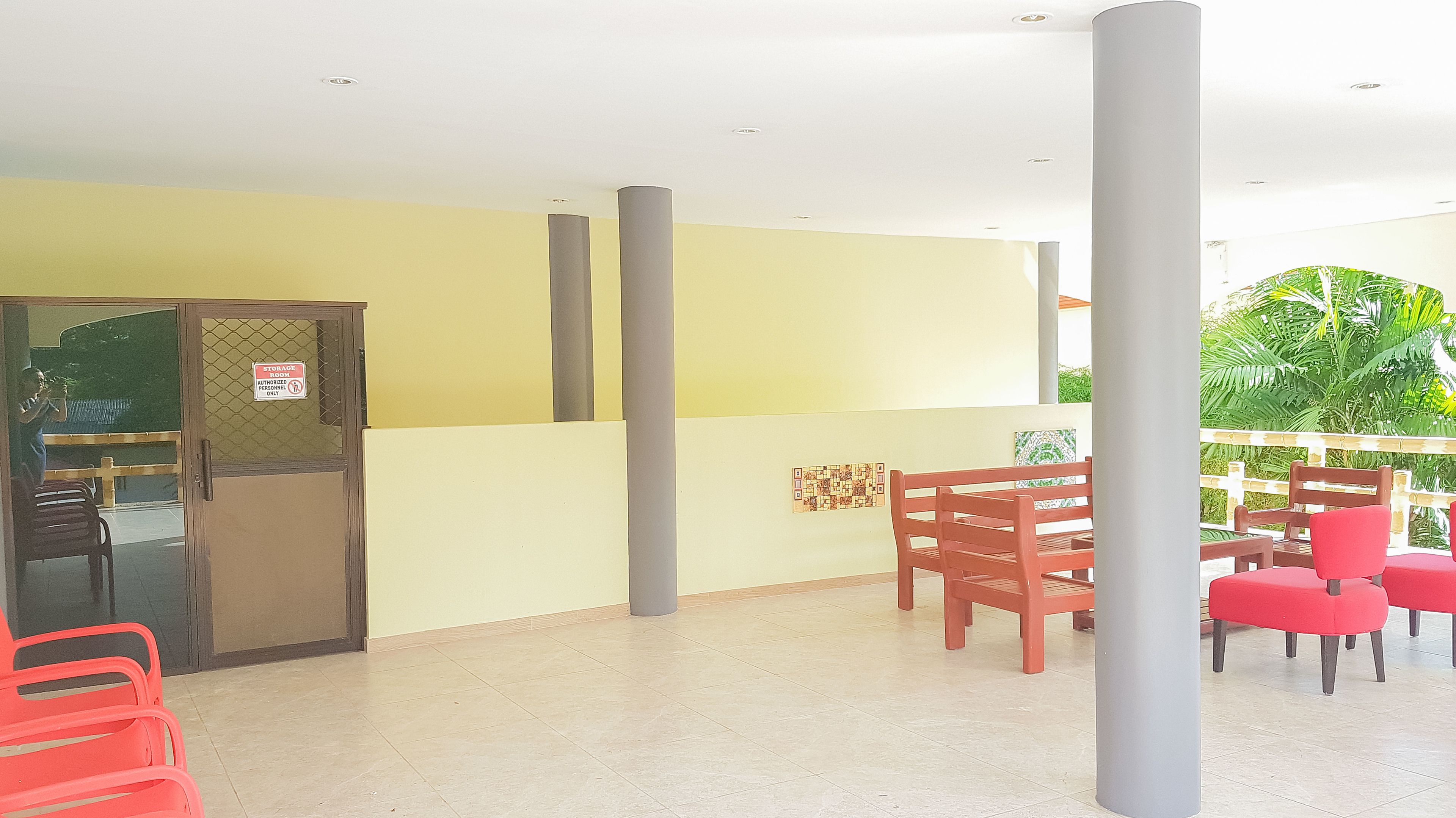 A reception area with a glass door, a storage room sign, and a seating area with red chairs.