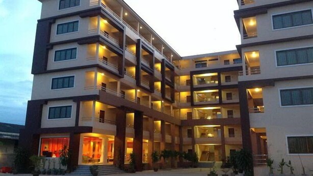 Un hotel de varios pisos con balcones, un patio central y una entrada bien iluminada.