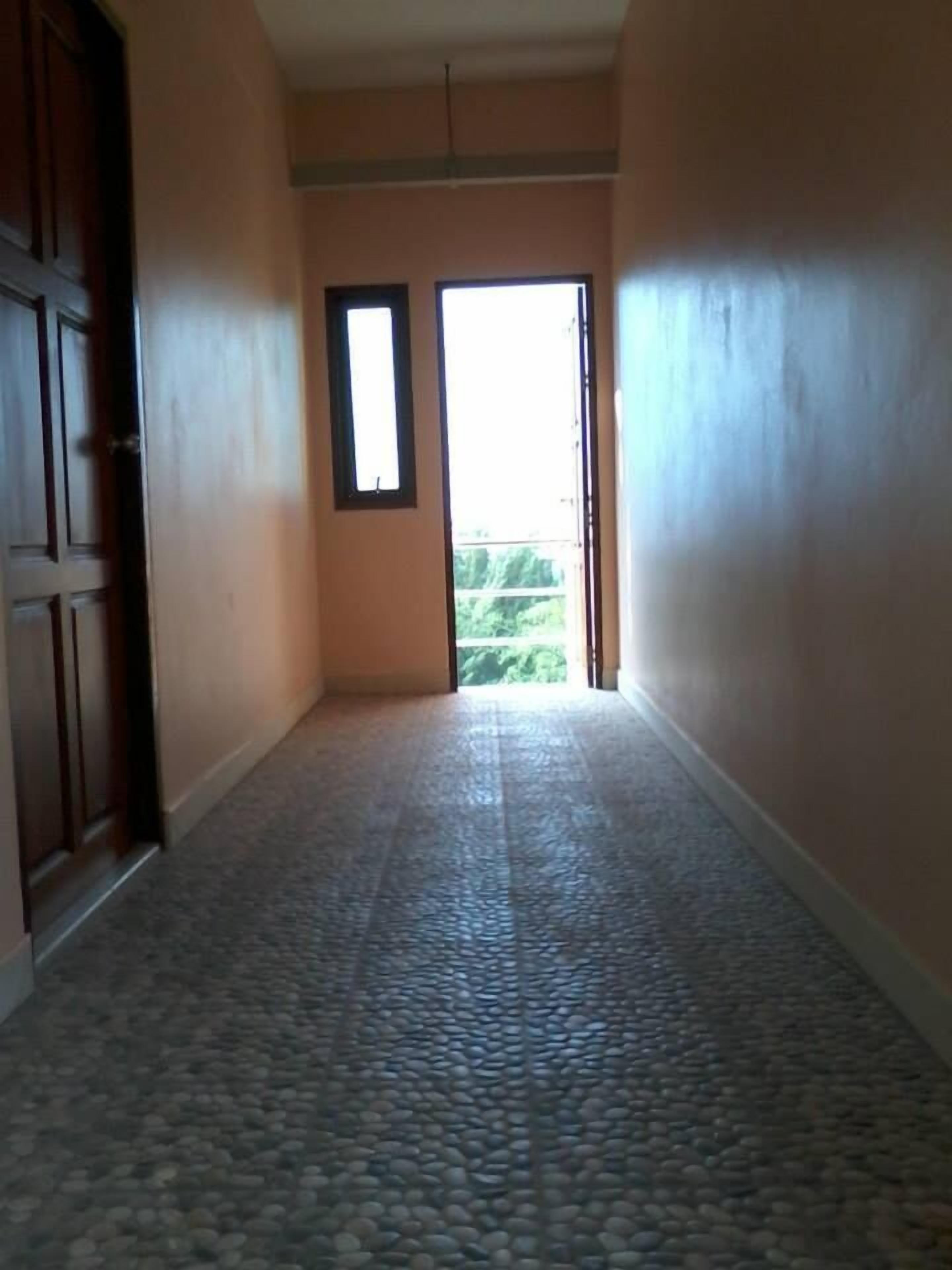 Un pasillo con piso de baldosas que conduce a una puerta con ventanal.