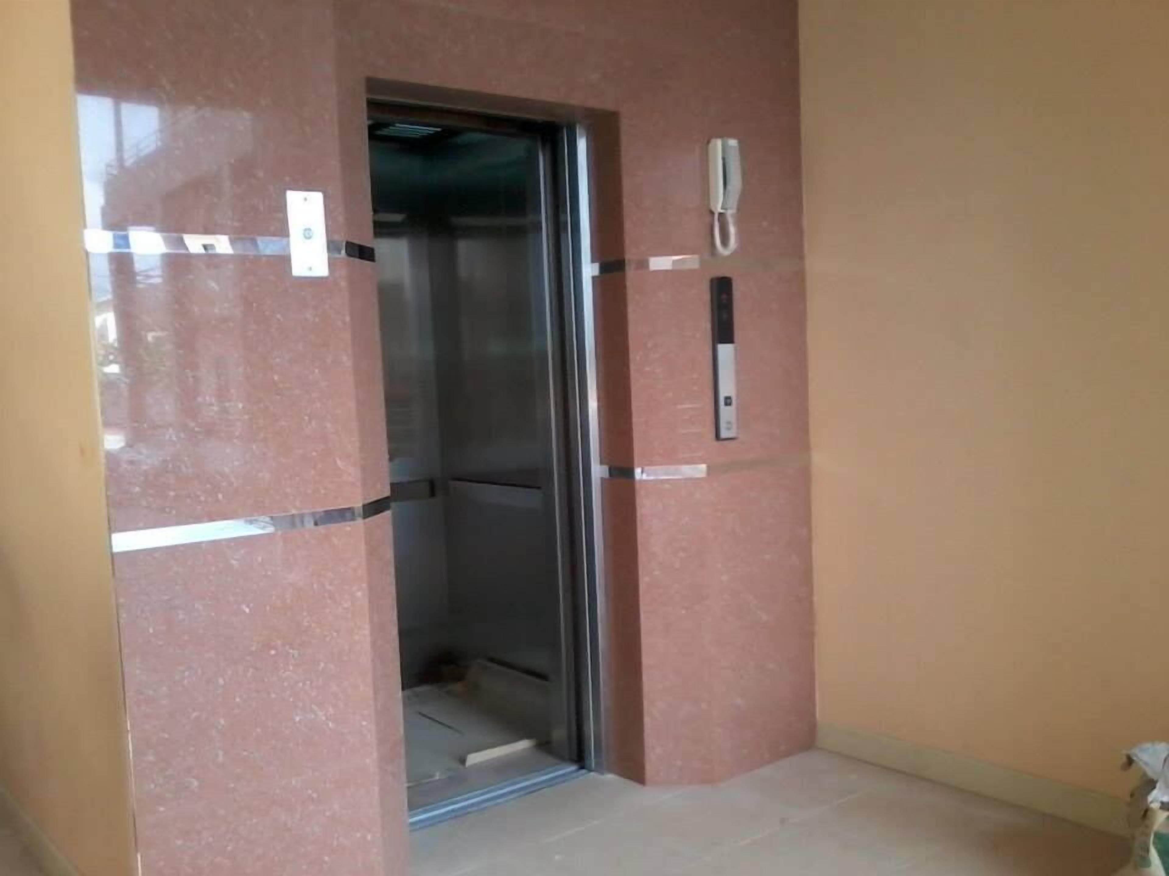 An elevator with a metallic interior, a wall-mounted phone, and a door with a metallic handle.