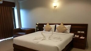 Habitación de hotel con una cama grande, dos almohadas, una mesita de noche con teléfono y una lámpara de pared.