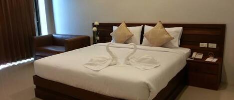 Habitación de hotel con una cama grande, dos almohadas, una mesita de noche con teléfono y una lámpara de pared.