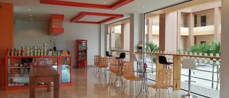 Un interior moderno con zona de comedor, máquina expendedora y vistas al exterior.