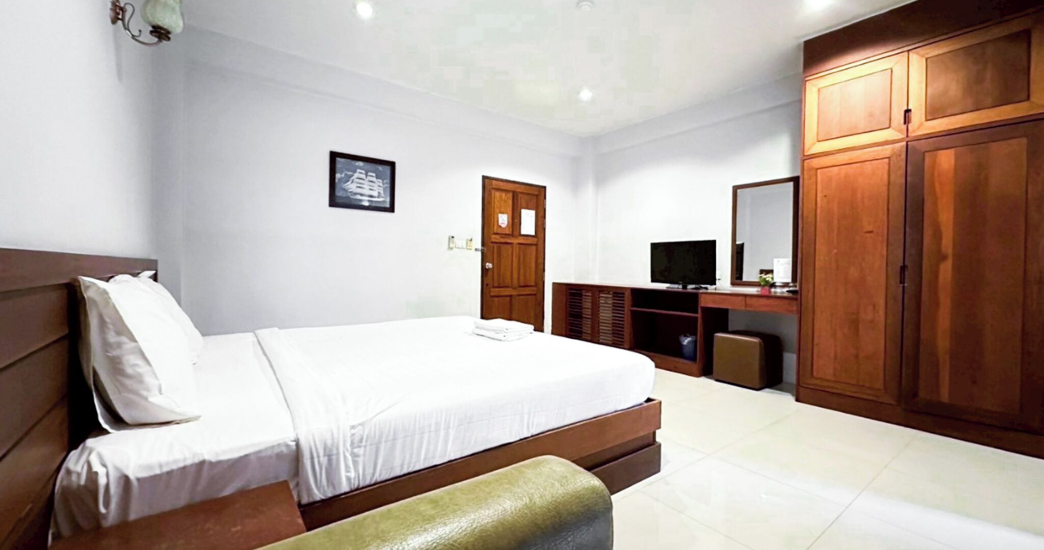 A bedroom with a bed, a desk, a television, and a wardrobe.