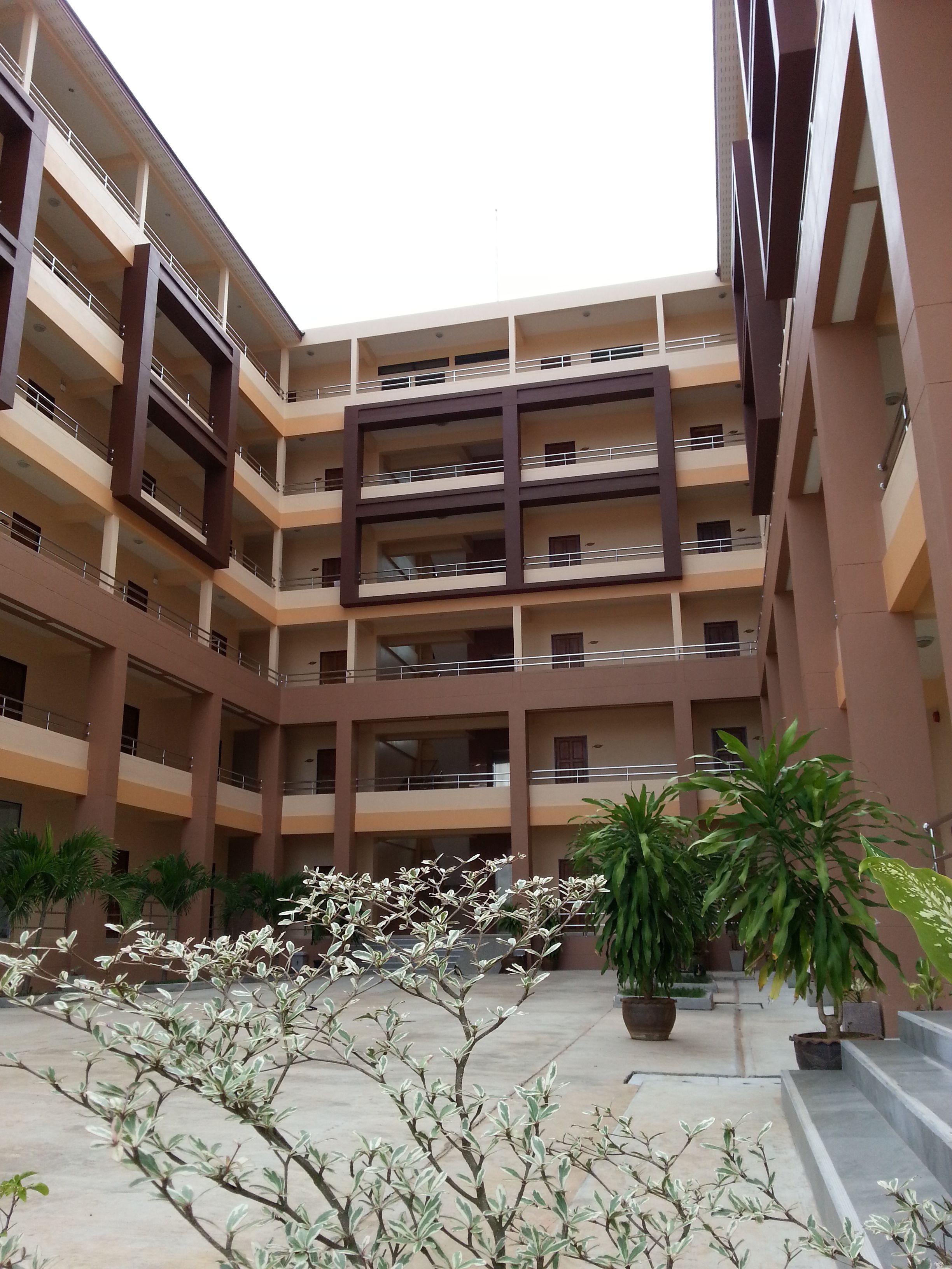 A multi-story building with balconies, potted plants, and a courtyard.
