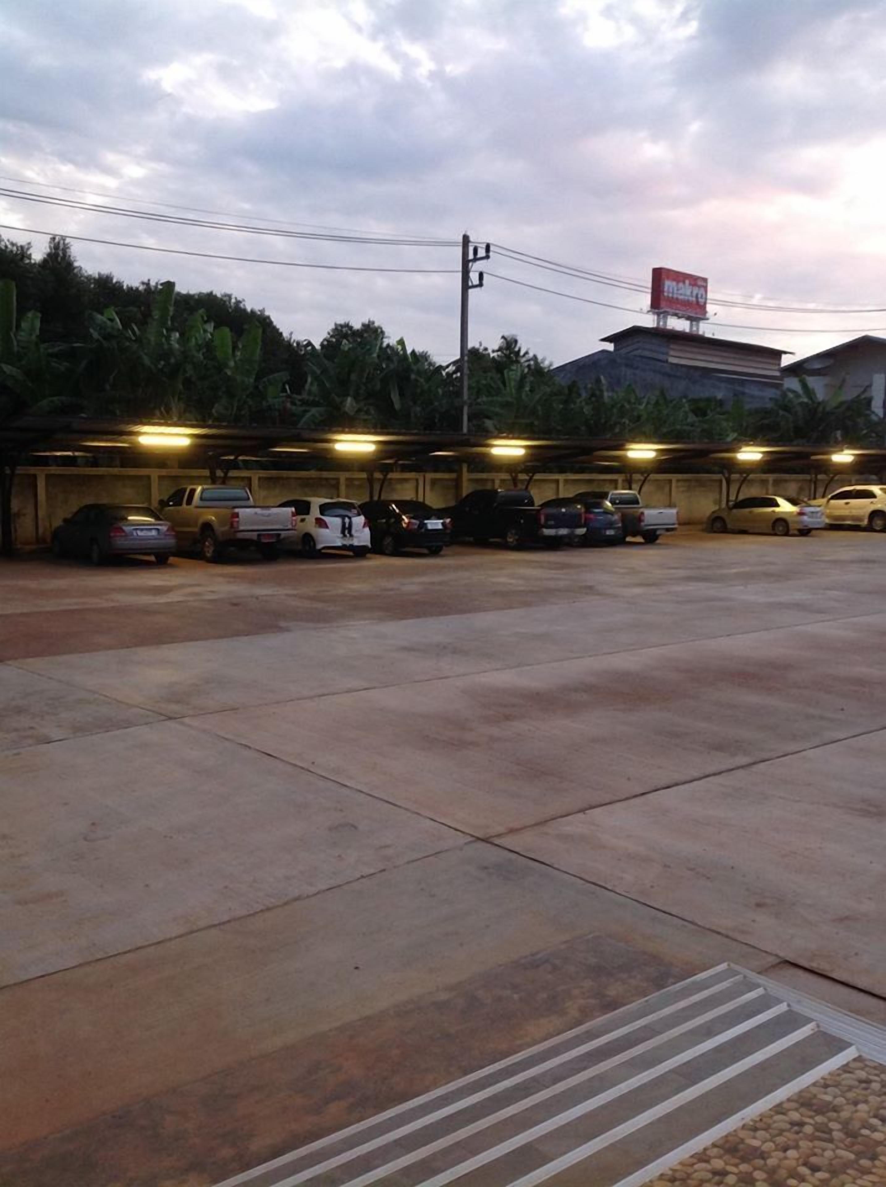 Uma área de estacionamento com vários carros e um edifício ao fundo.