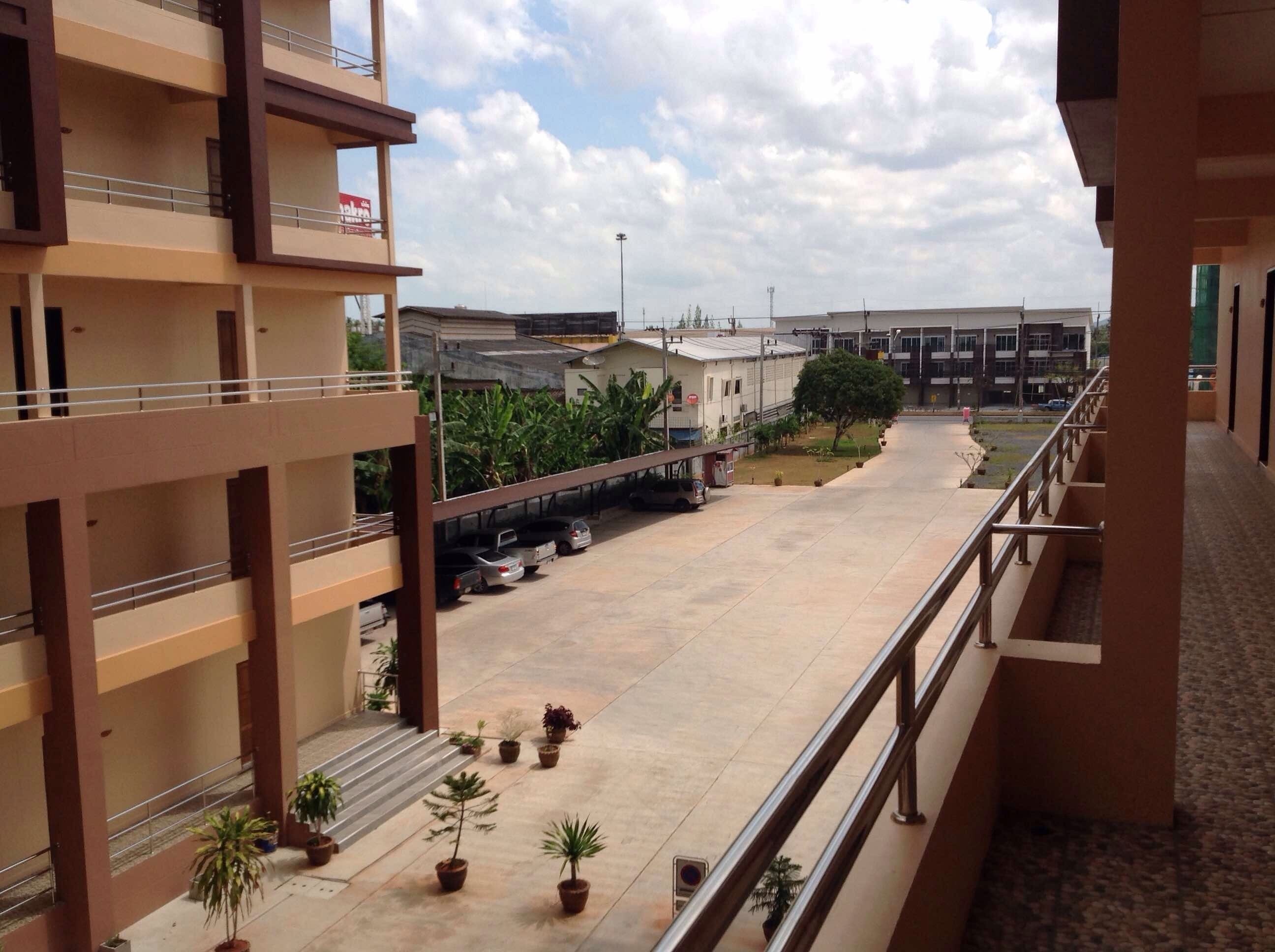 A multi-story building with balconies and a parking area.